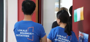 Zwei Studierende sind von hinten mit einem blauen T-Shirt "Lokale Erasmus Initiative" zu sehen.