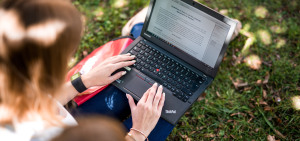 Eine Hochschulmitarbeiterin veröffentlicht Projektergebnisse im Freien auf ihrem Laptop.
