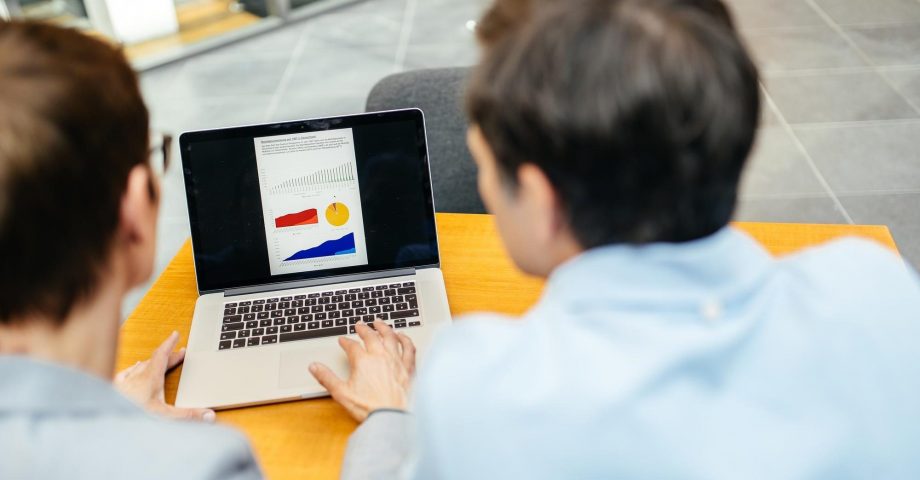 Zwei Frauen schauen sich Diagramme auf einem Laptop an.