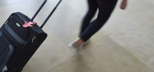 Ein Koffer mit Erasmus+ Kofferanhänger wird durch einen Flughafen gezogen.