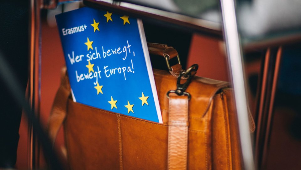 Eine Erasmus+ Mappe mit dem Slogan &quot;Wer sich bewegt, bewegt Europa&quot; blickt aus einer Tasche hervor