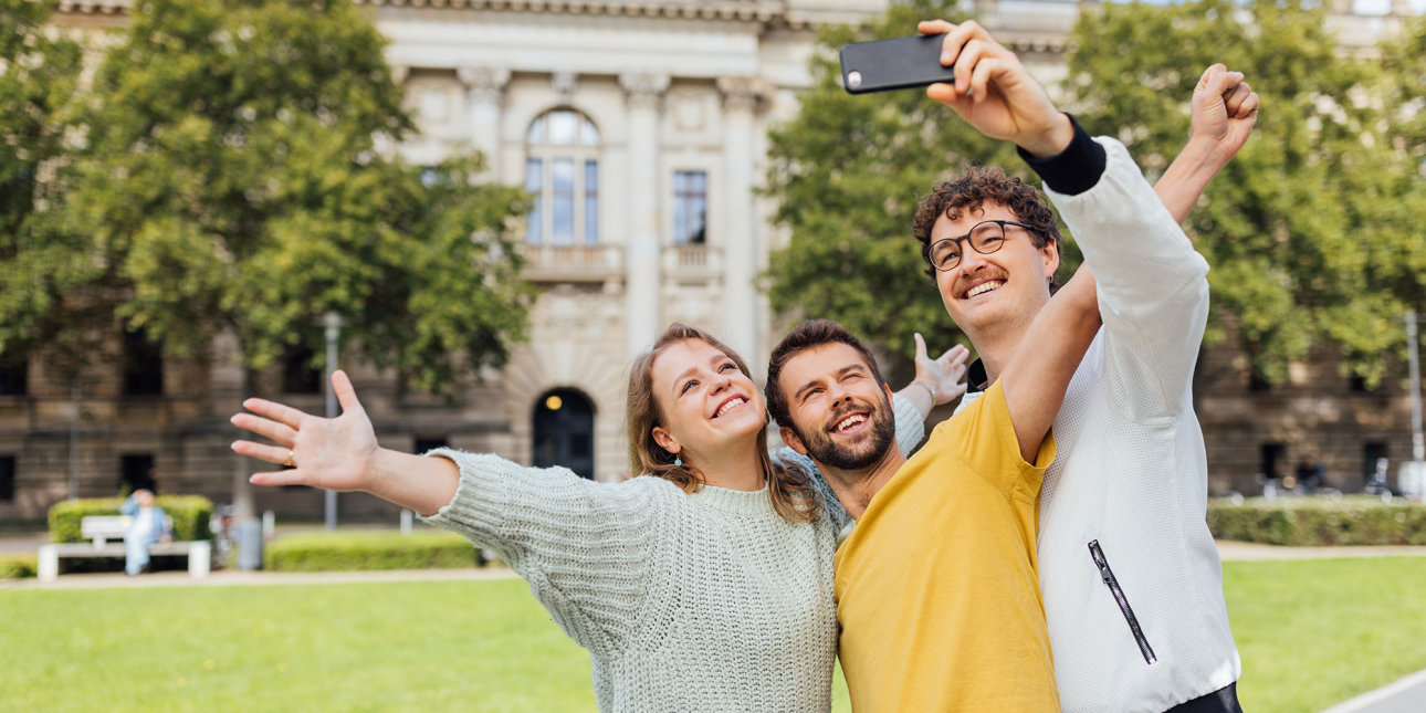 Studierende nehmen gemeinsam ein Selfie im Außenbereich ihrer Hochschule auf.