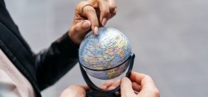 Frau zeigt mit Finger auf einen Teil eines Globus.