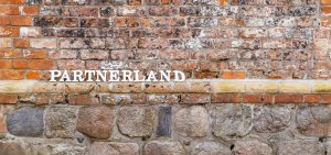 Motivbild: Holzbuchstaben "Partnerland" vor Backsteinmauer.