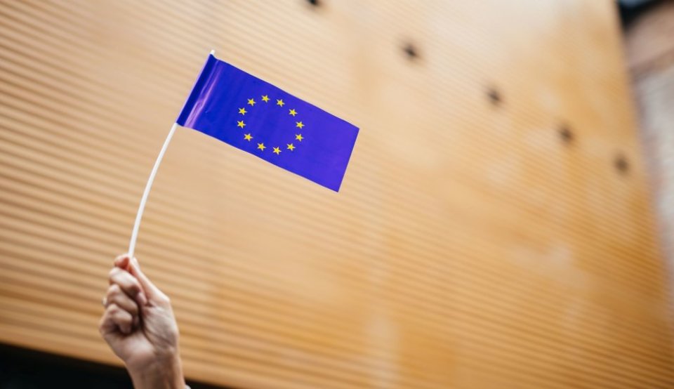 Hand hält Europaflagge als Papierfähnchen in die Höhe