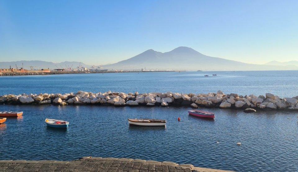 Hafen in Neapel mit Booten im Vordergrund und Bergen im Hintergrund