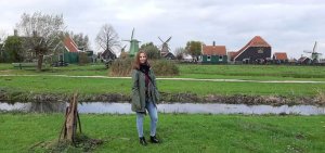 Studentin bei einem Spaziergang in niederländischer Landschaft mit Windmühlen im Hintergrund