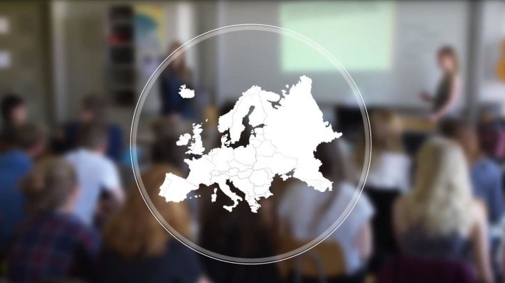 In dem Bildausschnitt aus dem Erasmus+ #kurzerklärt Video ist im Vordergrund eine Weltkarte eingeblendet, im Hintergrund ist eine Schulklasse während des Unterrichts zu sehen.