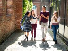 Vier Erasmus+ Studierende laufen über den Hochschulcampus auf dem Weg zu ihrem Europa macht Schule Projekt.