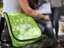 Sitzende Studentin mit einer grünen Erasmus+ Tasche