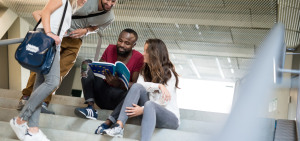 Vier Studierende sitzen auf einer Treppe in ihrer Hochschule und informieren sich über die Lokalen Erasmus+ Initiativen.