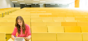 Studentin sitzt alleine in einem Hörsaal und lernt.