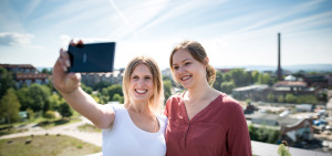 Selfie zweier Erasmus+ Studierenden vor städtischer Sommerlandschaft.