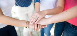 Symbolbild für studentische Zusammenarbeit: Studierende legen ihre Hände aufeinander