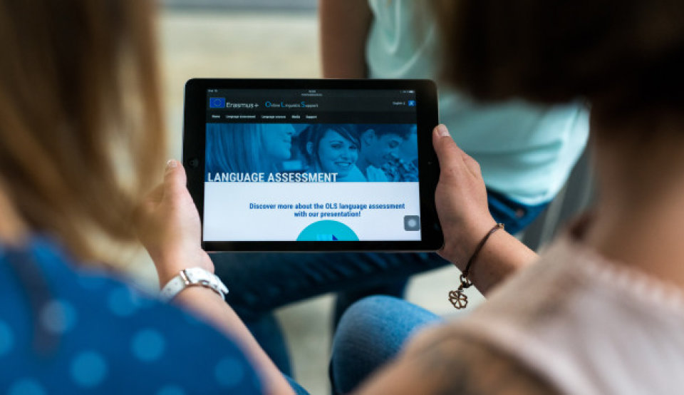 Zwei Studierende betrachten eine Online Seite von Erasmus+ auf einem Tablet.