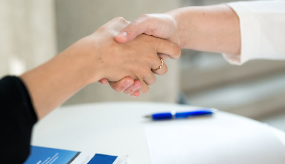 Zwei Hochschulmitarbeiter schütteln sich die Hand auf einer Konferenz zu der Erasmus+ Politikunterstützung.